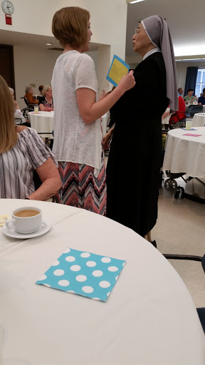 A gathering with guests enjoying conversation at tables, featuring a cup of coffee.
