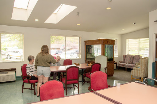 A bright and welcoming common area in a residential facility, featuring individuals engaged in conversation around a table.