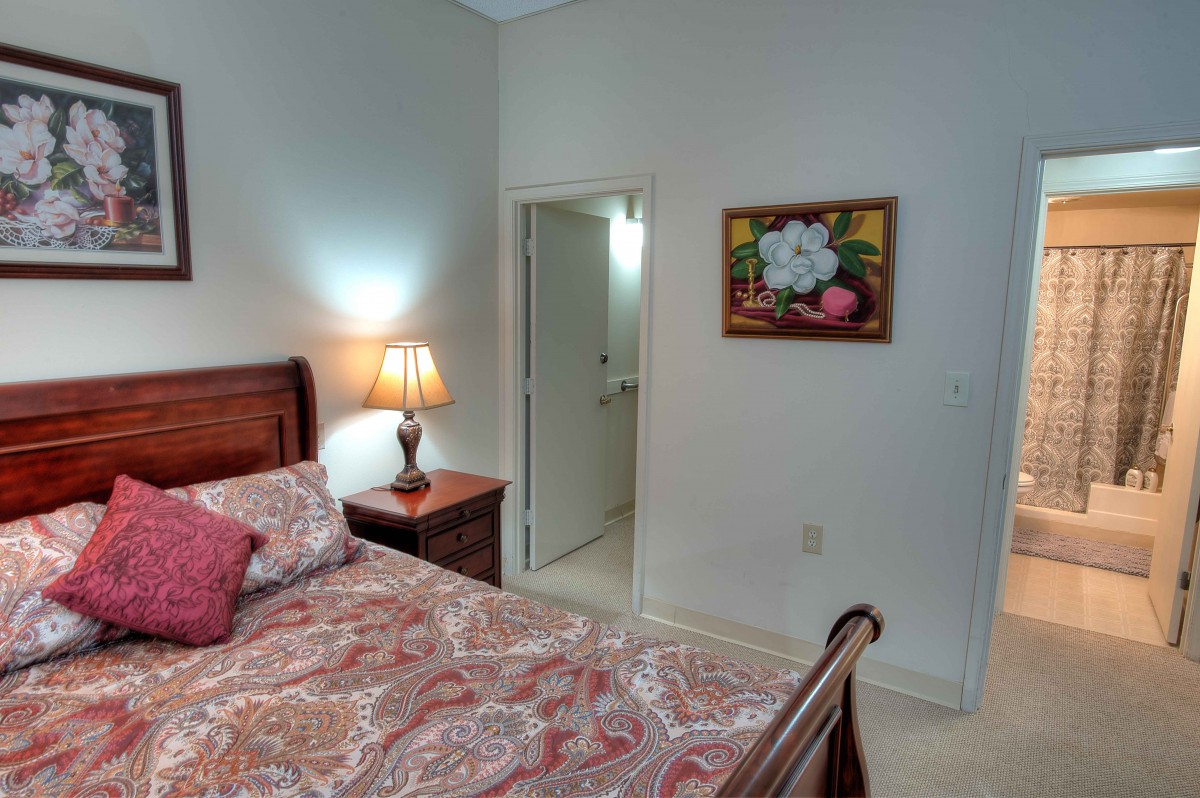 A cozy bedroom with wooden furniture, a floral bedspread, and decorative wall art.