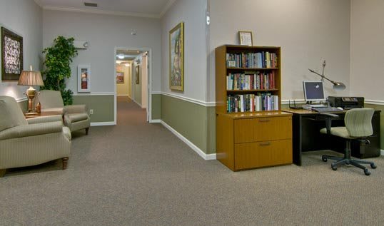 A waiting room with a bookshelf and a hallway leading to other rooms.