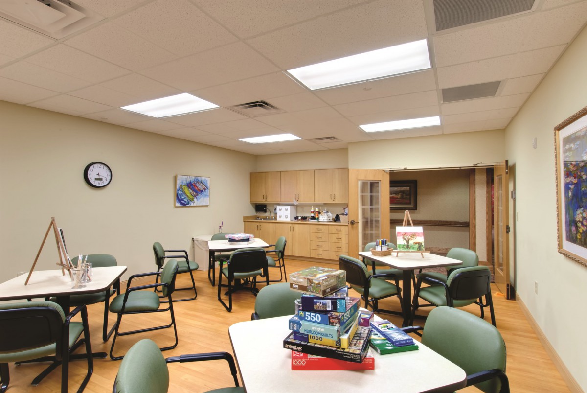 An office break room with tables, chairs, and a small kitchen area.