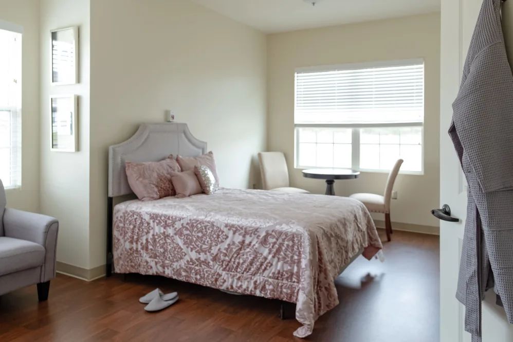 A cozy bedroom with a neatly made bed and natural light streaming through the window.