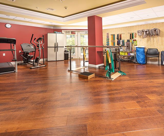 A well-equipped gym with various exercise machines and a wooden floor.