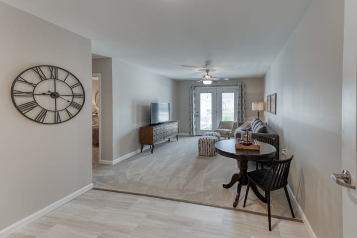 A modern living room with neutral tones, featuring a round table and chair set, a ceiling fan, and stylish furnishings.