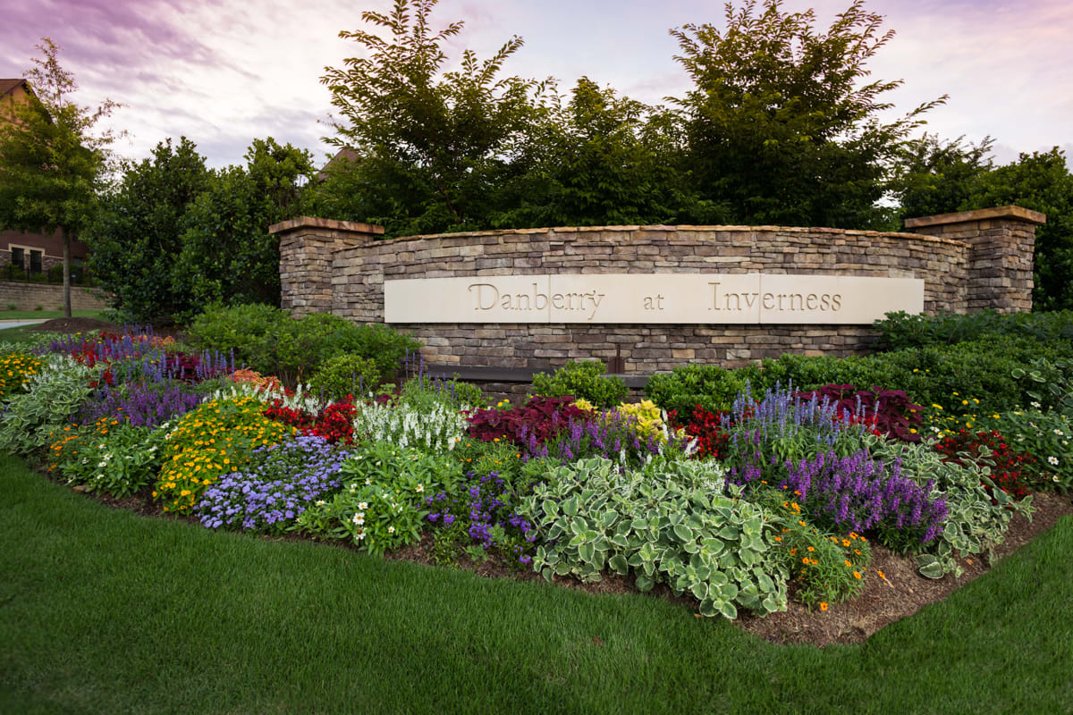 Beautifully landscaped garden with vibrant flowers in front of a stone sign.