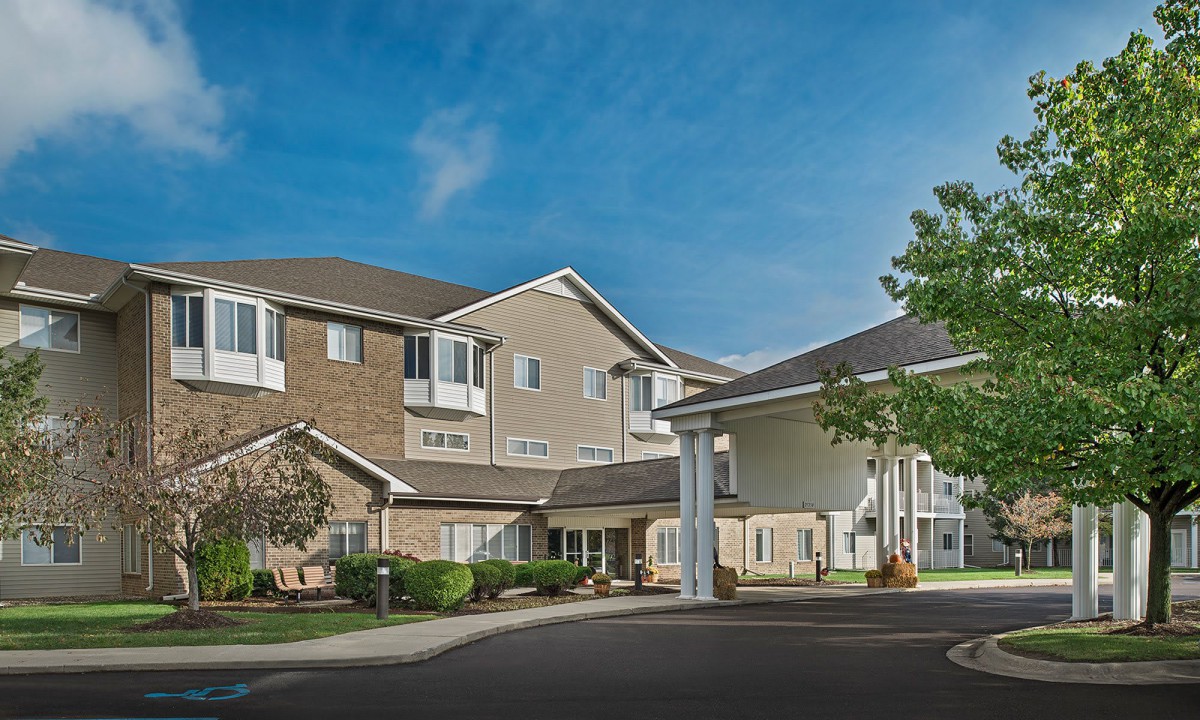 A residential housing complex with landscaped surroundings under a clear blue sky.