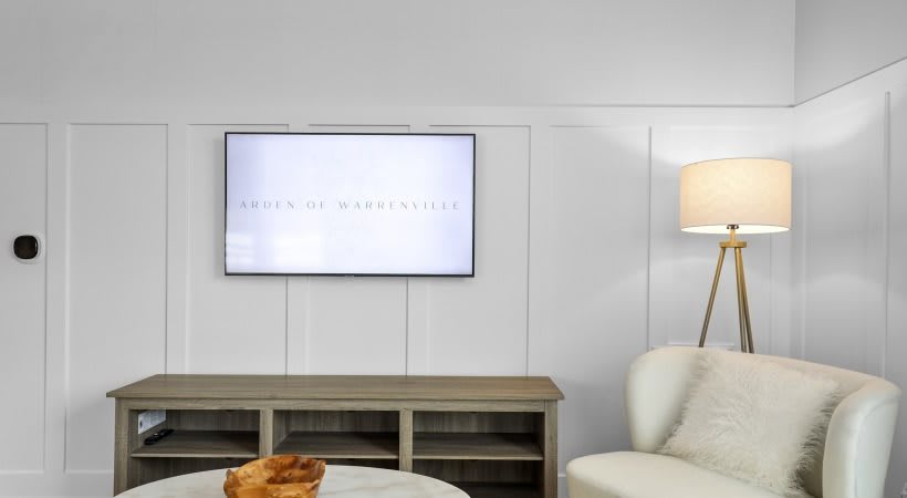 A cozy living room with a wall-mounted television and stylish furniture.