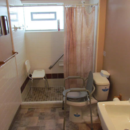 An accessible bathroom with a shower chair and grab bars for safety.