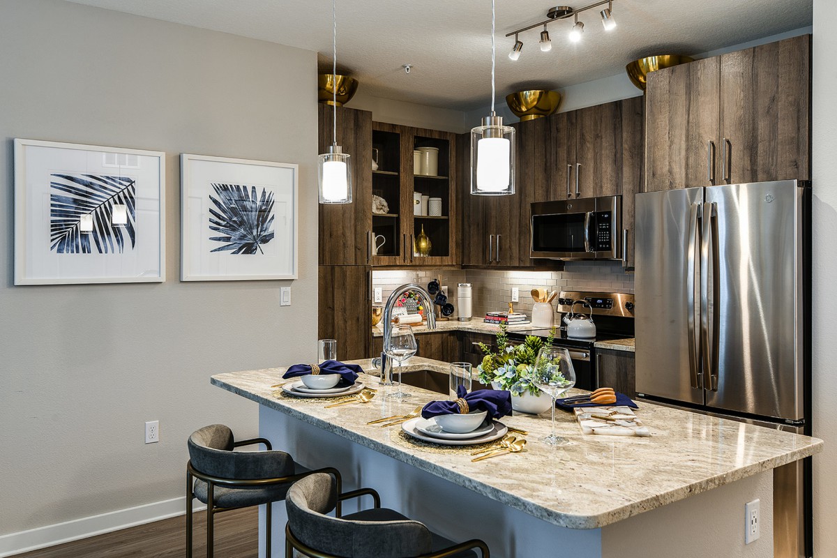 A modern kitchen with a stylish island counter, featuring bar stools and elegant pendant lighting.