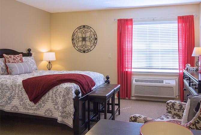 A cozy bedroom with a comfortable bed, elegant decor, and vibrant red curtains.