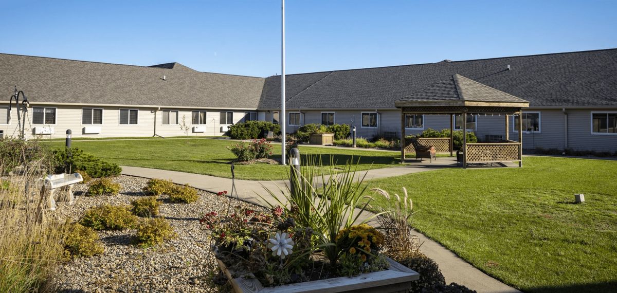 A courtyard featuring landscaped gardens and a central walkway under a clear, sunny sky.