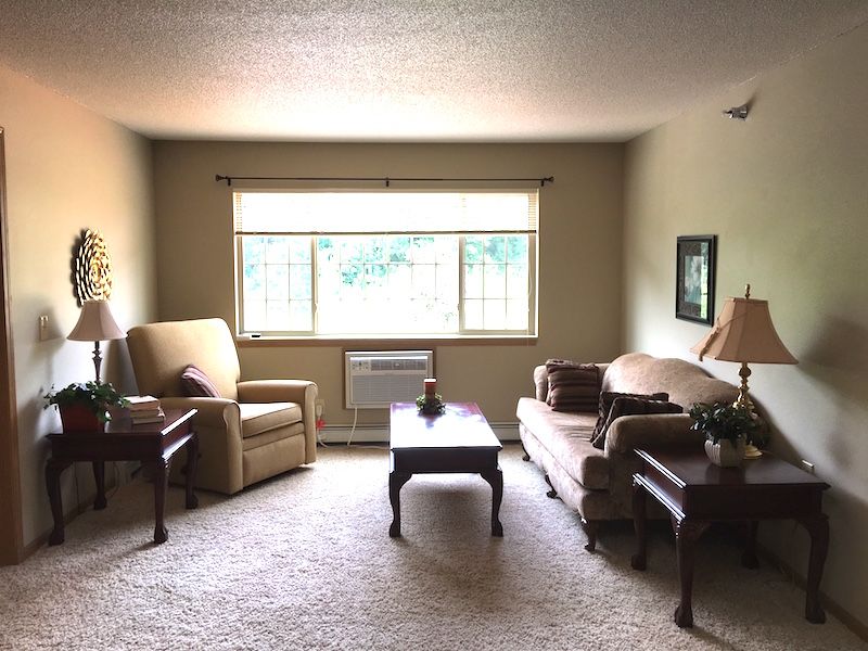 A cozy living room with a sofa, armchair, and coffee table facing a large window.