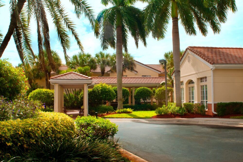 A sunny view of a building surrounded by palm trees and well-maintained landscaping.