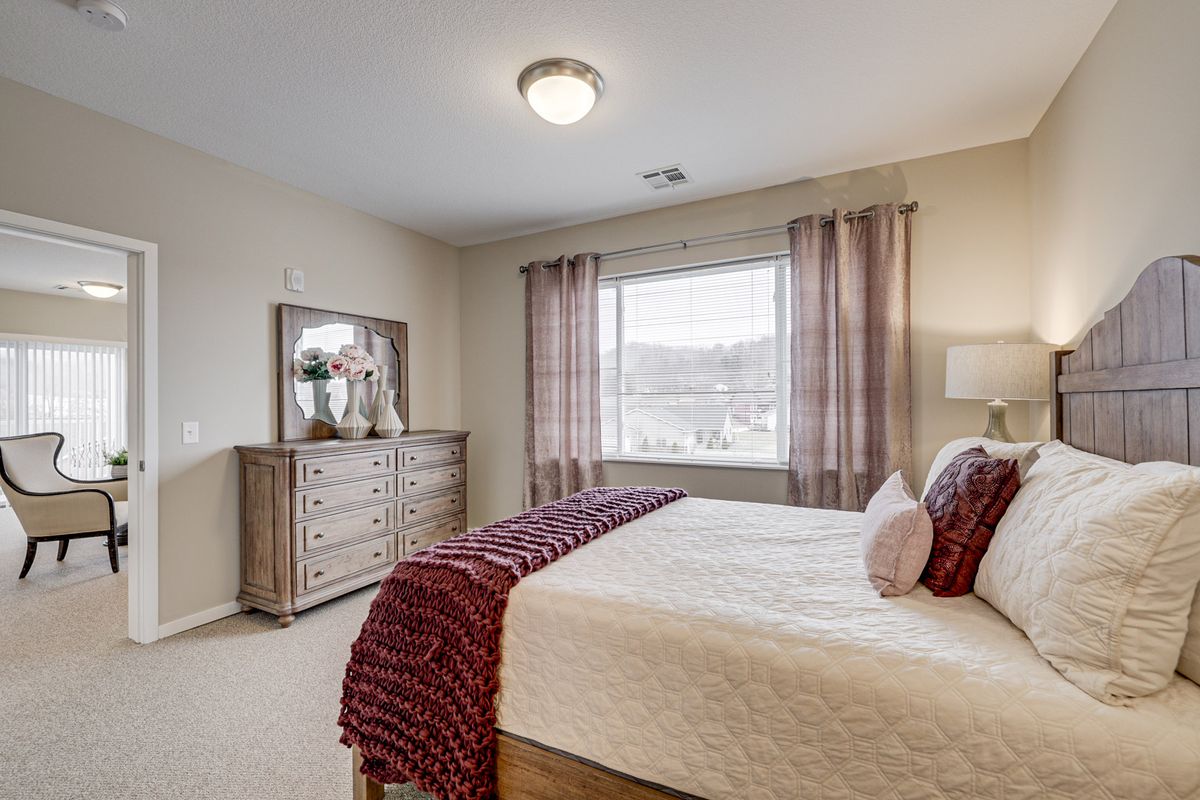 A cozy bedroom with a large bed and dresser, featuring soft lighting and elegant curtains.