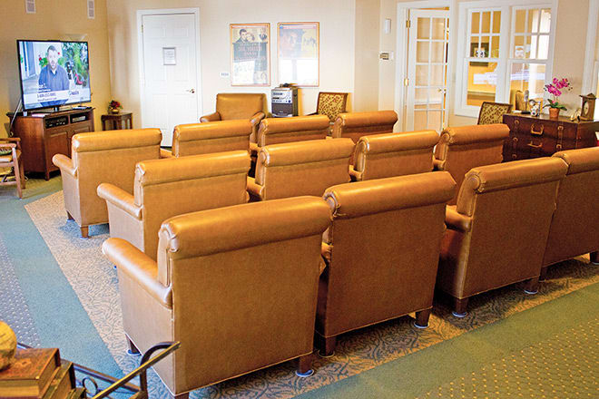 A cozy theater room with rows of comfortable leather chairs arranged for viewing.