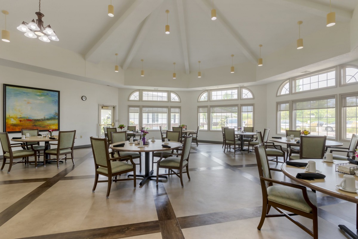 A spacious dining area with elegant tables and chairs, featuring abundant natural light through large windows.