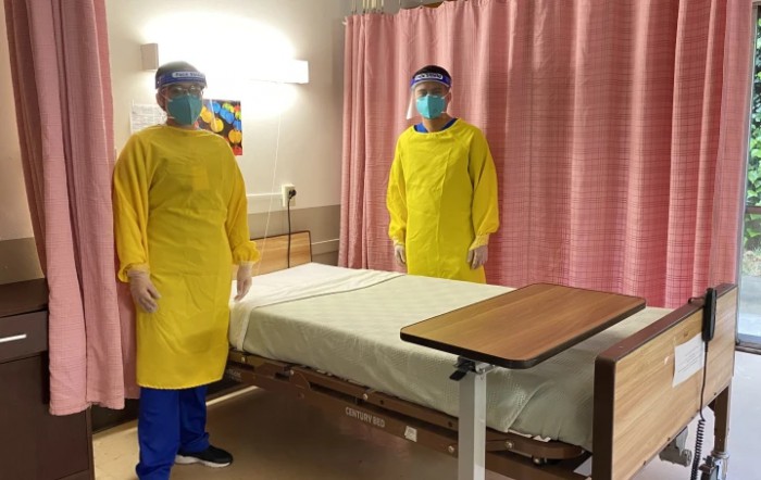 Healthcare workers wearing PPE in a hospital room.