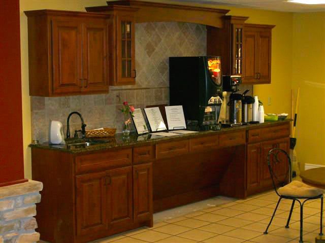 A kitchen setup featuring wooden cabinets, a counter with various appliances, and tiled flooring.