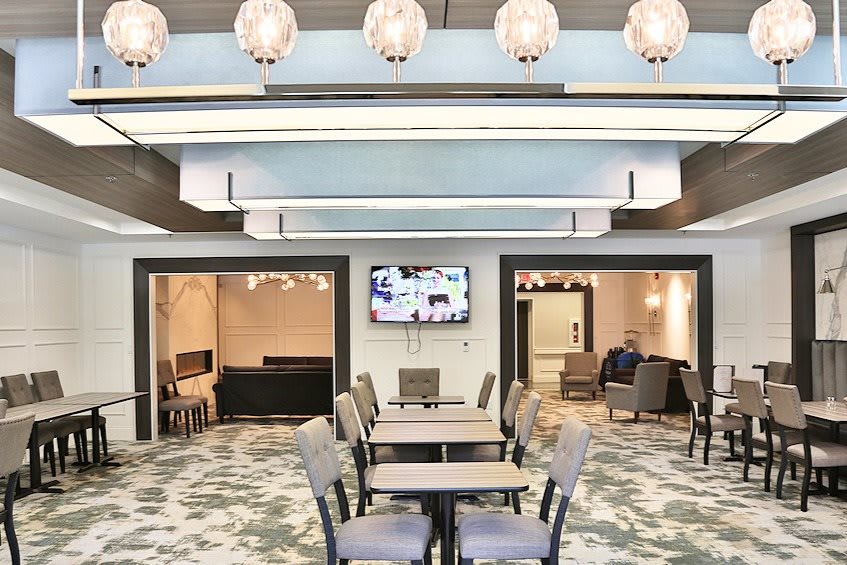 A modern lounge area with elegant chandeliers, tables, and seating.
