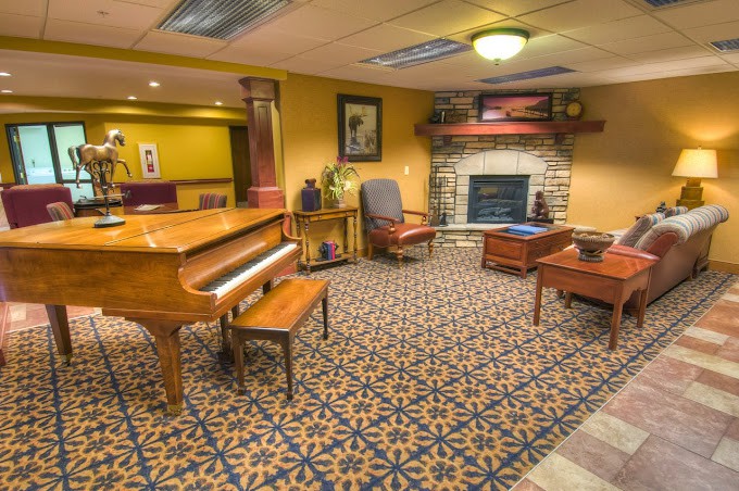 A cozy living room with a grand piano and a fireplace.