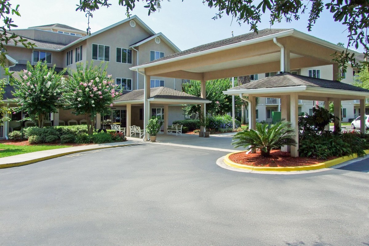 A well-maintained building entrance with a covered driveway and landscaped surroundings.