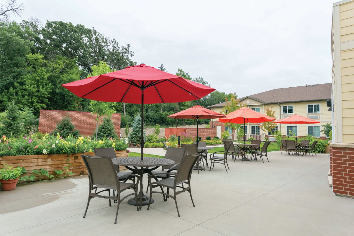 Outdoor patio area with tables, chairs, and red umbrellas.