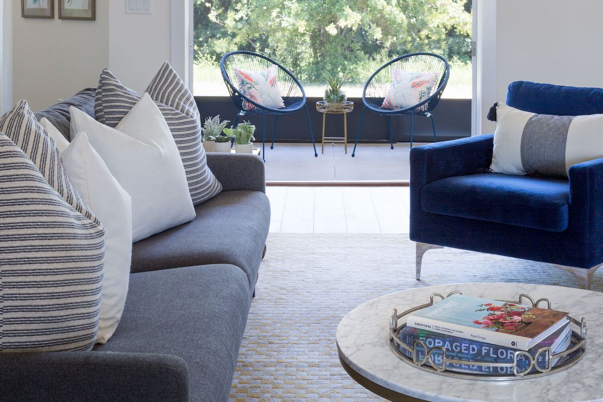 A modern living room with stylish furniture and a view of outdoor seating.