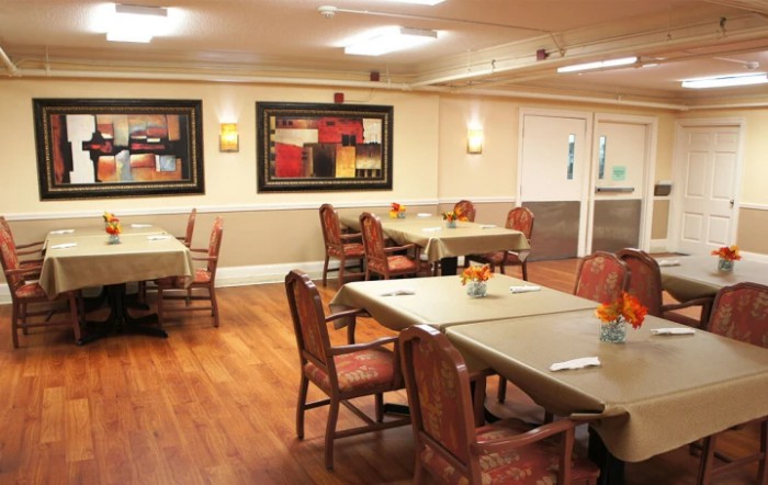 A cozy dining area with neatly arranged tables and chairs, adorned with colorful artwork on the walls.