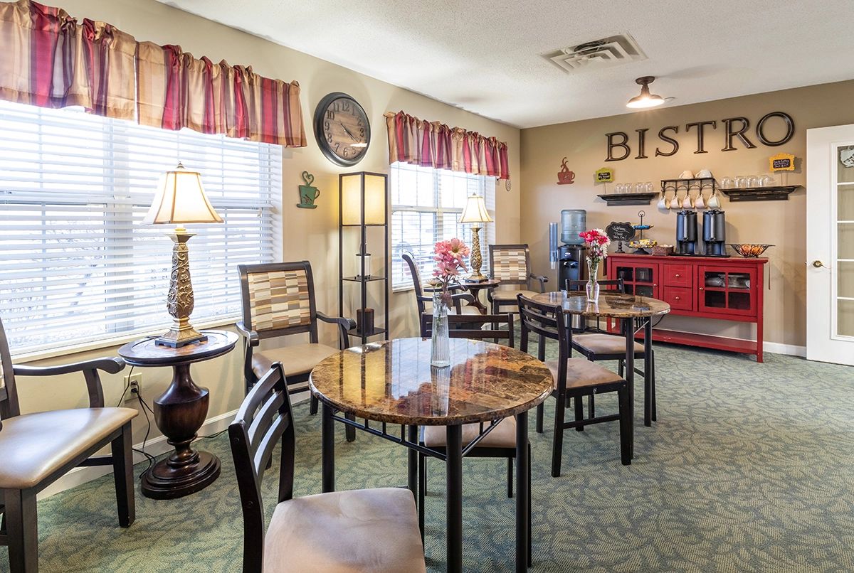A cozy indoor bistro with multiple tables and chairs, decorated with elegant lamps and curtains.
