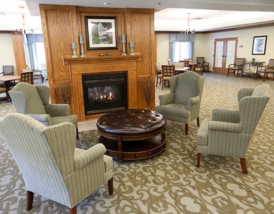 A cozy living room setup with four chairs around a wooden coffee table in front of a fireplace.
