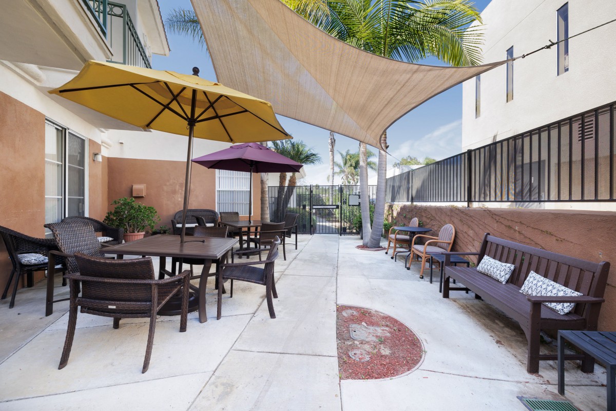 A cozy outdoor patio with umbrellas and shade sails providing a relaxing seating area.