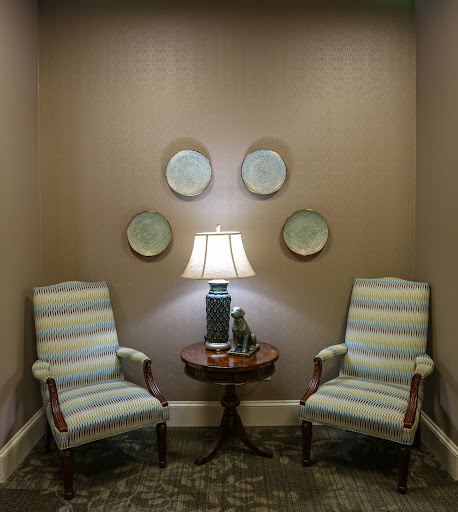 A cozy seating area with striped chairs and a lamp, adorned by decorative plates on the wall.
