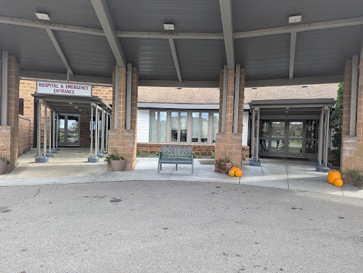 The main entrance of a building, featuring a spacious waiting area with benches and a covered canopy.