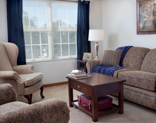 Cozy living room with sofa, armchair, and coffee table near a large window.