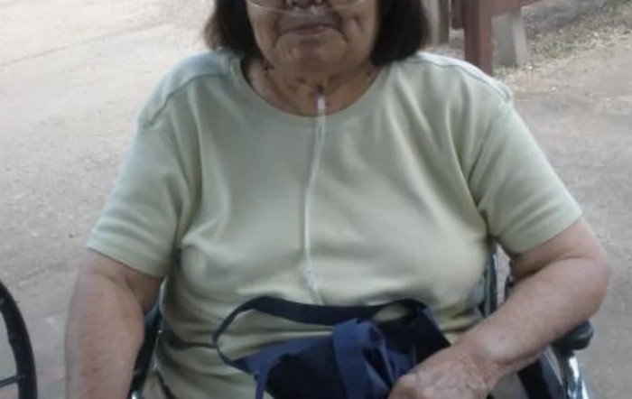 An elderly woman in a wheelchair with an oxygen tube.