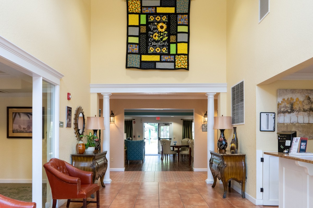 A spacious foyer with a colorful quilt hanging on the wall and elegant furnishings.