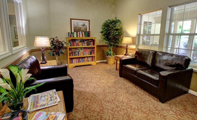 A cozy waiting room with sofas, a bookshelf, and warm lighting.