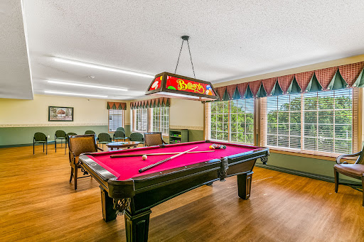 A well-lit game room featuring a vibrant pink pool table and comfortable seating, perfect for leisure and recreation.