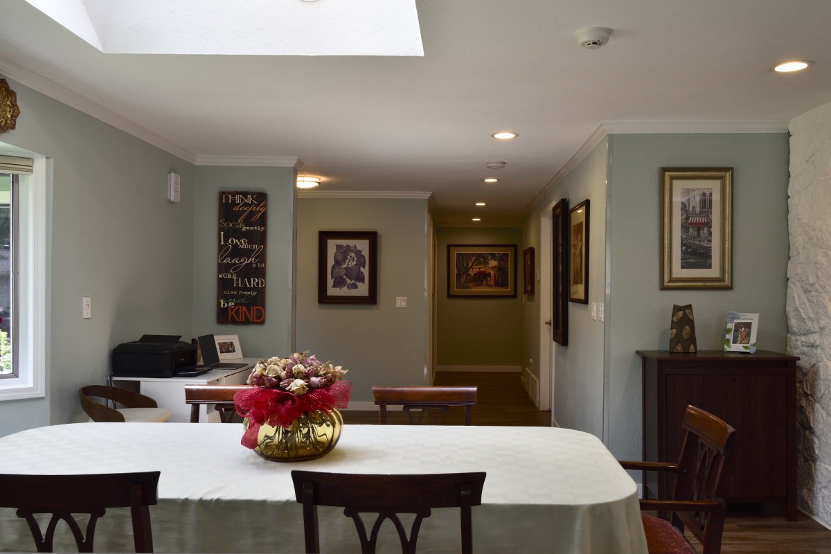 A cozy dining room with a table and chairs, decorated with a flower arrangement and artwork on the walls.