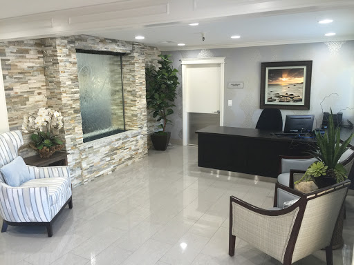 A modern office waiting room featuring sleek furniture and a calming water feature.