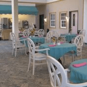 An indoor cafe with teal tablecloths and white chairs.