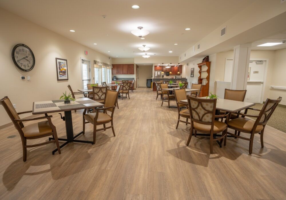 A spacious dining area with tables and chairs arranged neatly on a wooden floor.
