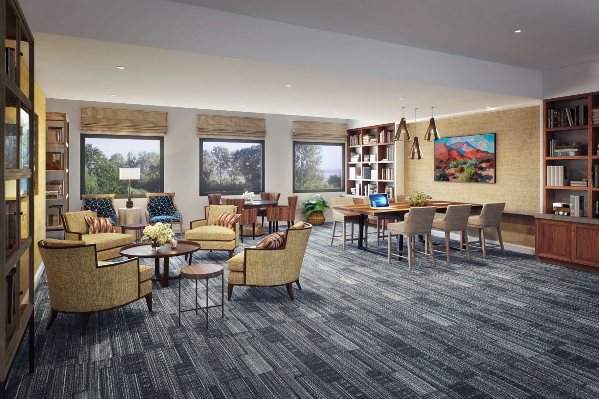 A modern lounge with comfortable seating, large windows, and a cozy reading area equipped with bookshelves.