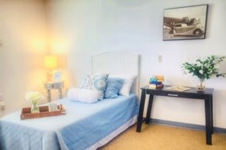 A cozy bedroom with blue bedding and soft lighting.