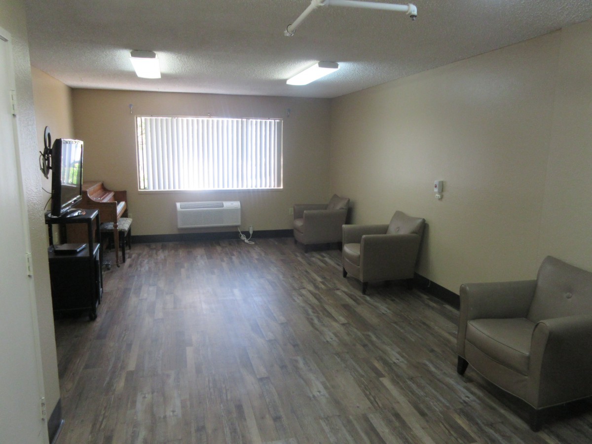 An empty room with chairs along the walls and large windows letting in light.