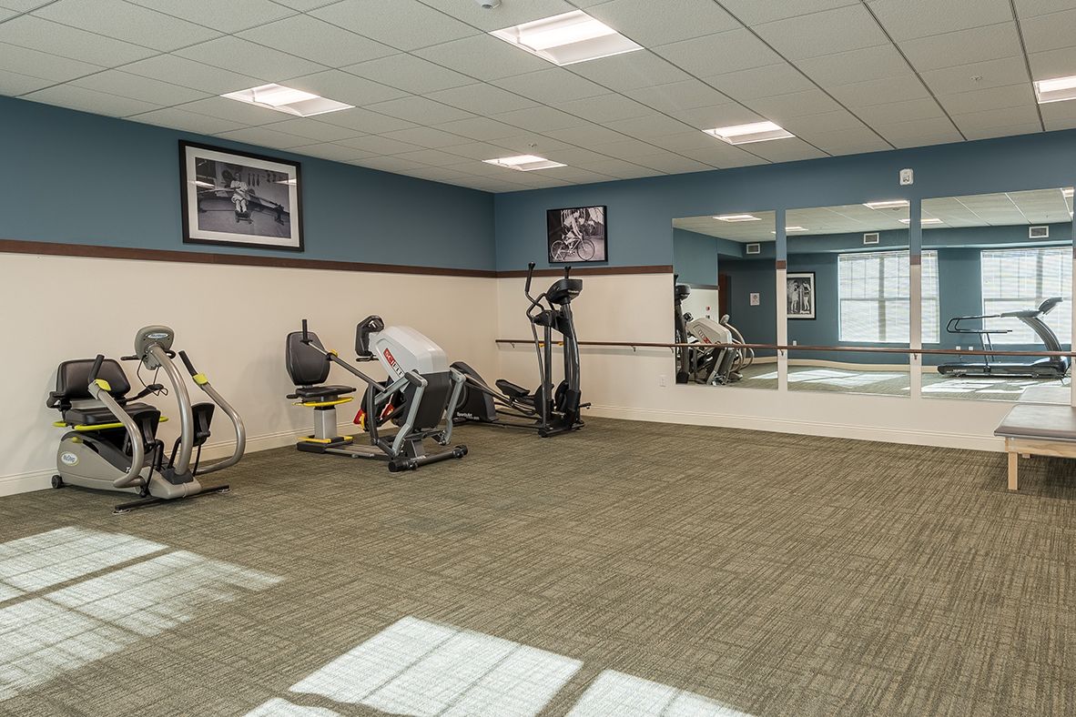 A modern gym with exercise equipment and a mirror-lined wall.