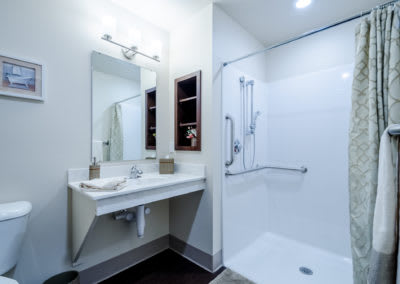 A modern, minimalist bathroom with a sleek sink, large mirror, and spacious shower area.