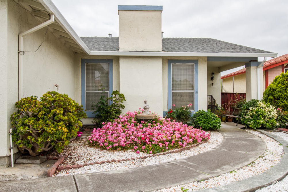 A charming house with a well-maintained front yard featuring a flower garden and a driveway.