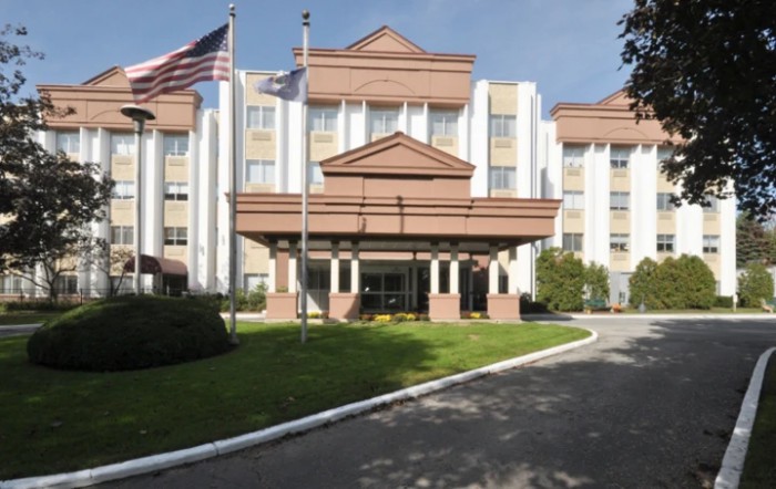 A hotel entrance with flags and landscaped surroundings.