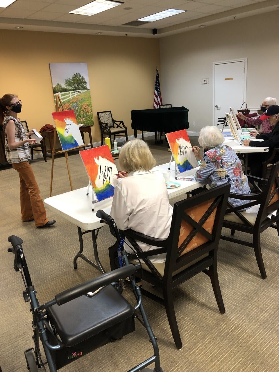 A group of seniors participating in a painting class, each working on their artwork at tables with easels.